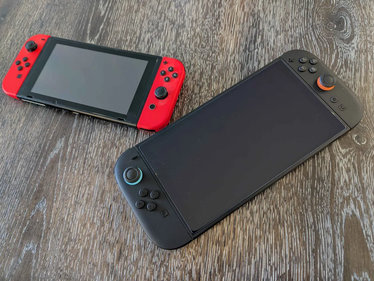 A photo by the author of a Nintendo Switch and a Nintendo Switch 2 sitting on a wooden table.
